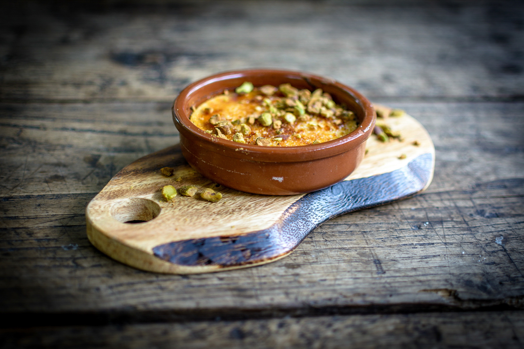 A close-up image showing a creme brulee dessert on a table outside.