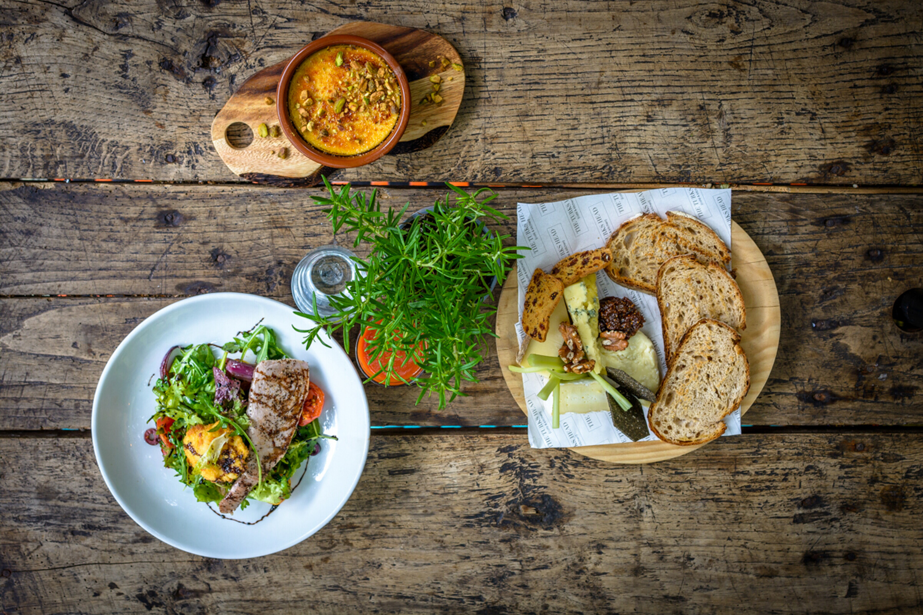 A flat-lay image showing various food plates on an outside table from above.